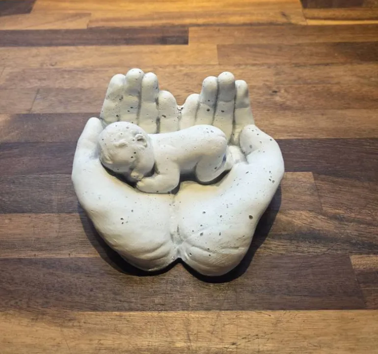 Hænder med baby i hvid cement